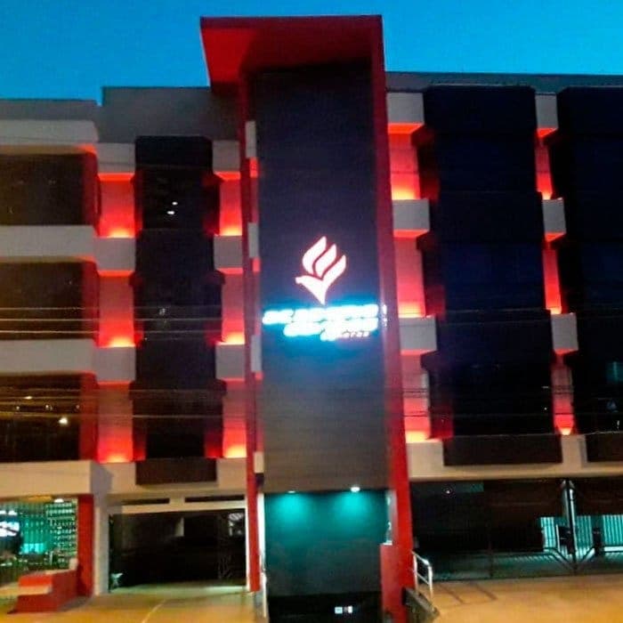 Fachada de edifício comercial após o retrofit, à noite, com iluminação vermelha nas colunas.