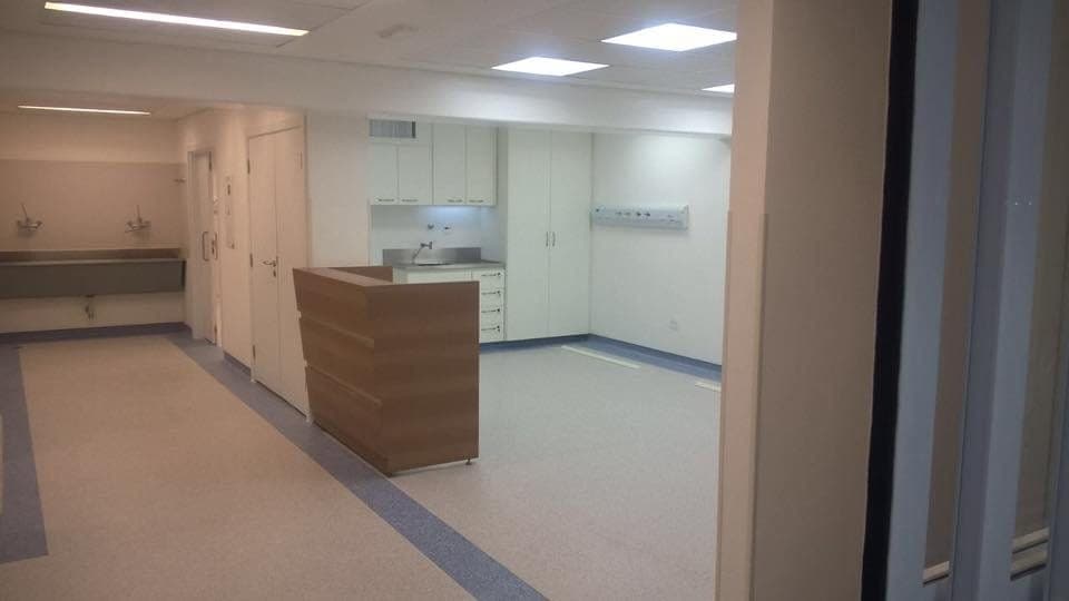 Recepção hospitalar reformada, com balcão de madeira e piso vinílico.
